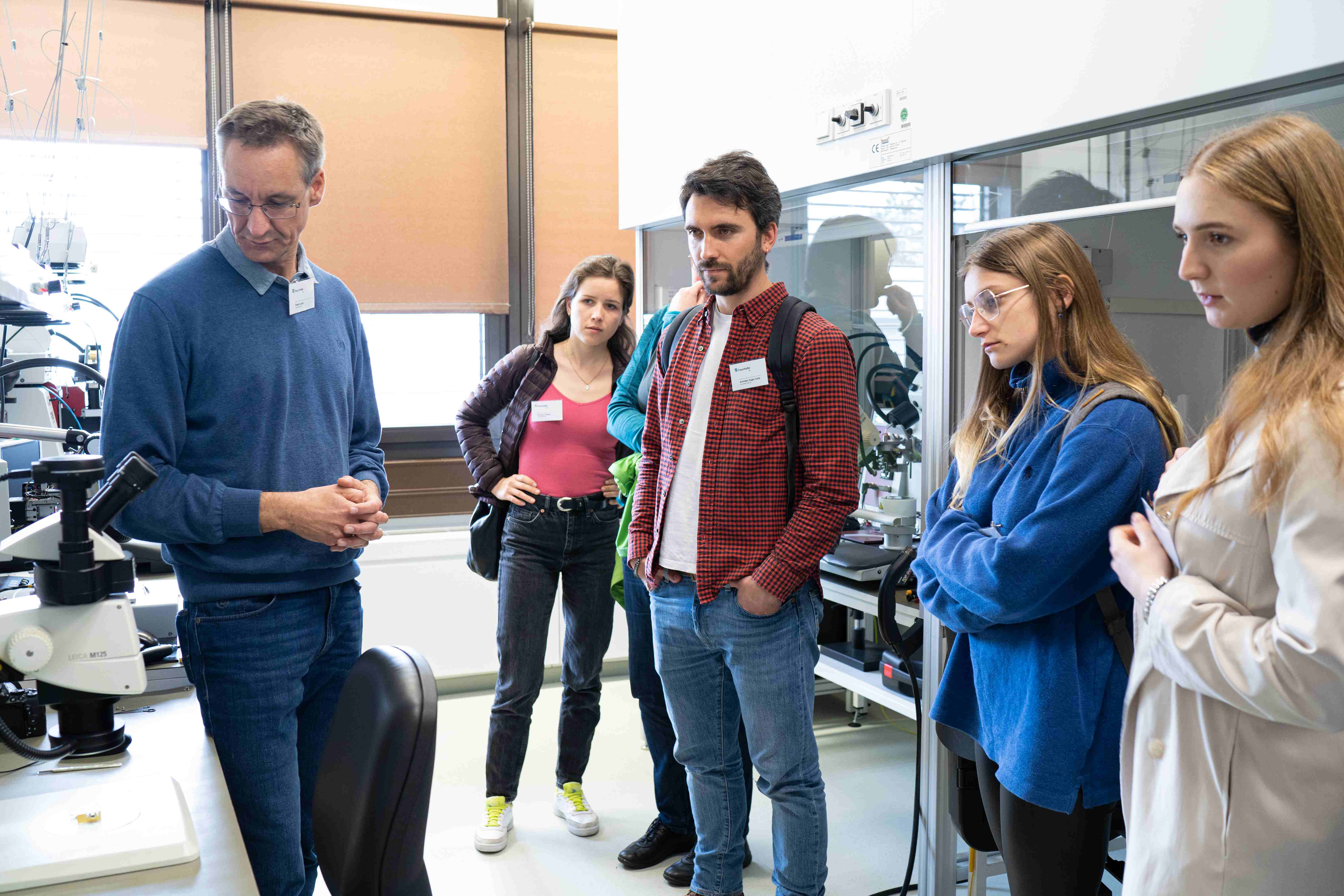Mehrere Studierende und ein Forscher blicken auf ein Messgerät im Labor.
