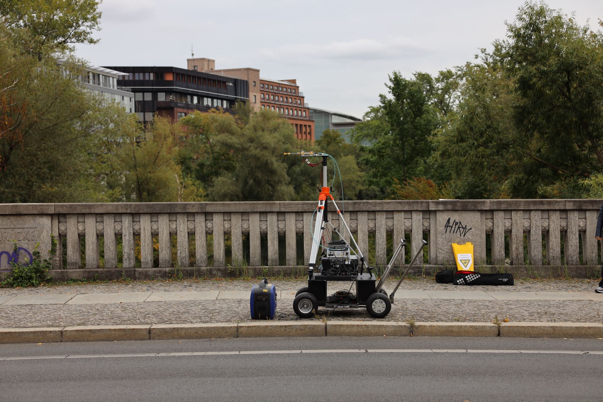 Zu sehen ist der Empfänger-Messaufbau auf Rädern an einer Verkehrsbrücke mit Bäumen und Gebäuden im Hintergrund.