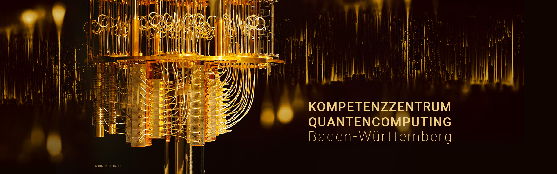 IBM Quantencomputer goldorange auf schwarzem Hintergrund mit Schriftzug "Fraunhofer Kompetenzzentrum Quantencomputing Baden-Württemberg"