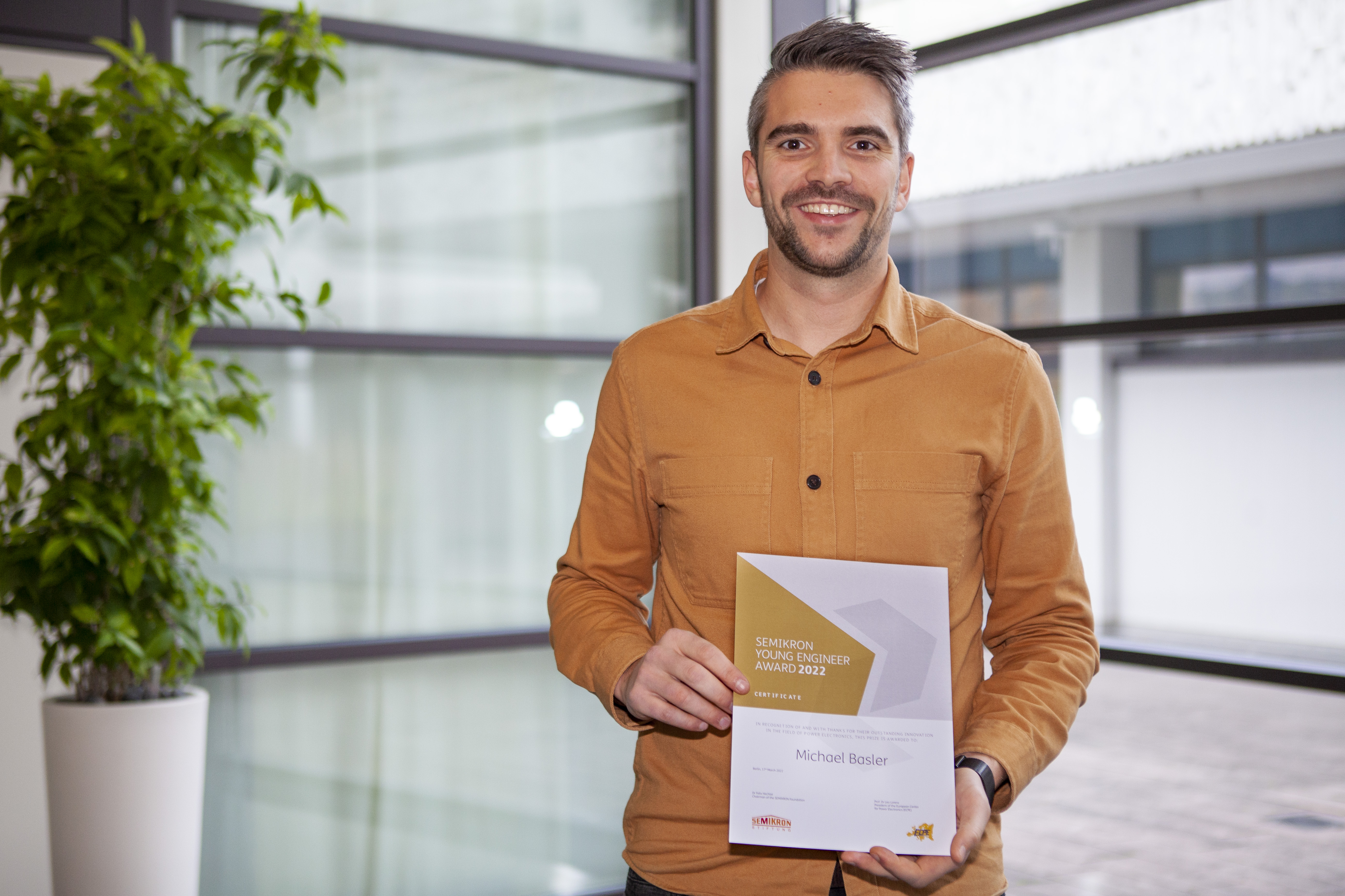 Michael Basler holds his certificate for the SEMIKRON Young Engineer Award 2022 in his hands.