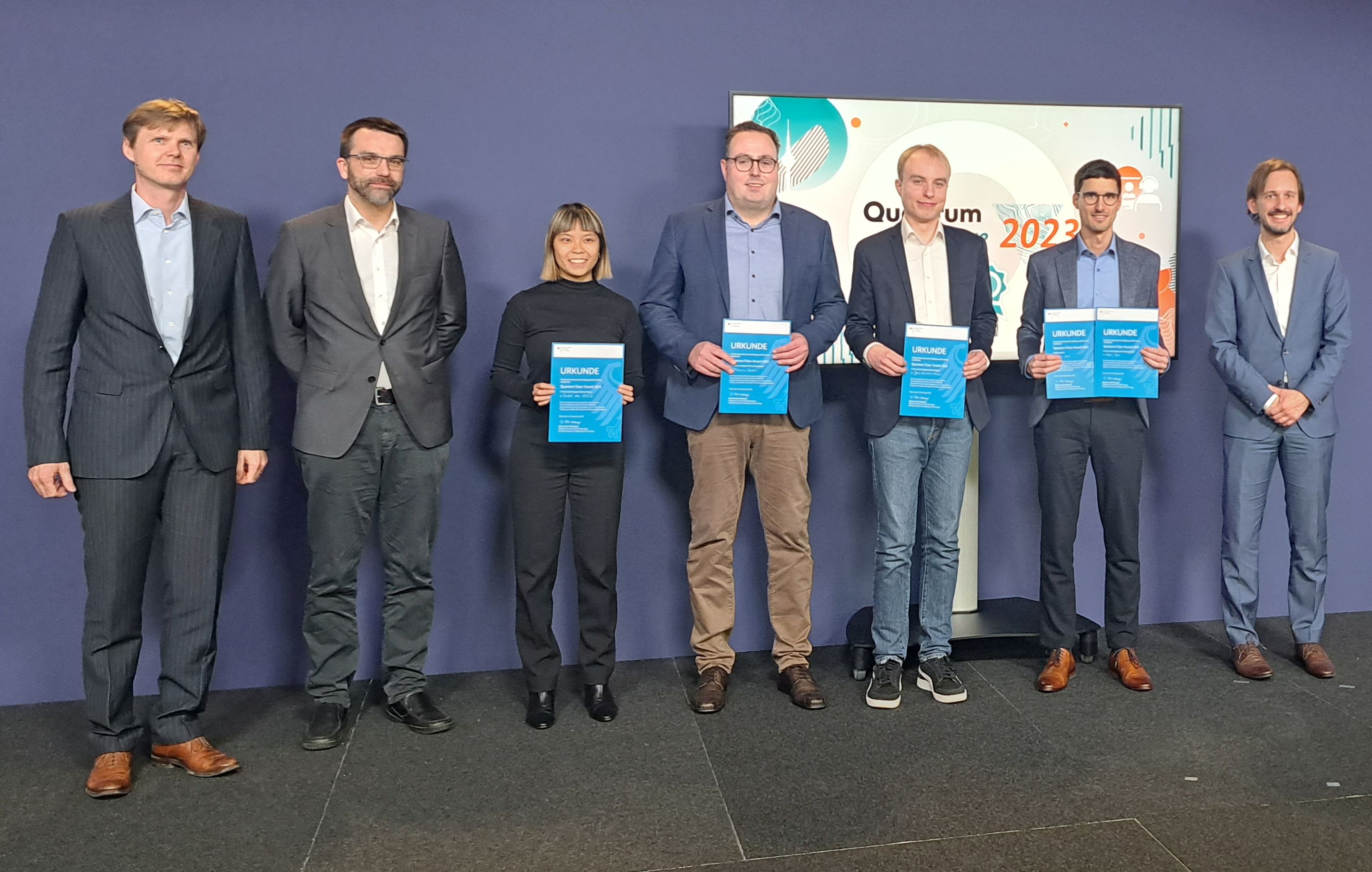 Dr. Felix Hahl (2nd from right, Fraunhofer IAF and University of Freiburg) with Dr. Max Riedel (ZEISS Innovation Hub @ KIT, jury), Dr. Sebastian Blatt (planqc, jury), Isabel Nha Minh Le (RWTH Aachen University, 2nd place Master), Dr. Thomas Gerster (TU Braunschweig, 2nd place PhD), Jens-Christian Drawer (University of Oldenburg, 1st place Master) and Dr. Wolfgang Müssel (Federal Ministry of Education and Research, jury) at the award ceremony in Berlin