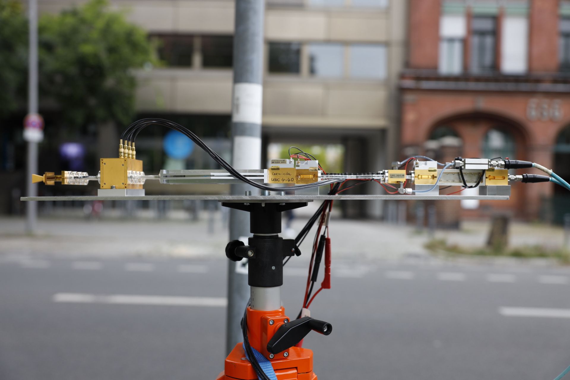 Measurement setup of the KONFEKT demonstrator with E-band module High-frequency components are connected to form a measurement setup; in the background, two buildings and a traffic road can be seen in a slightly blurred way.