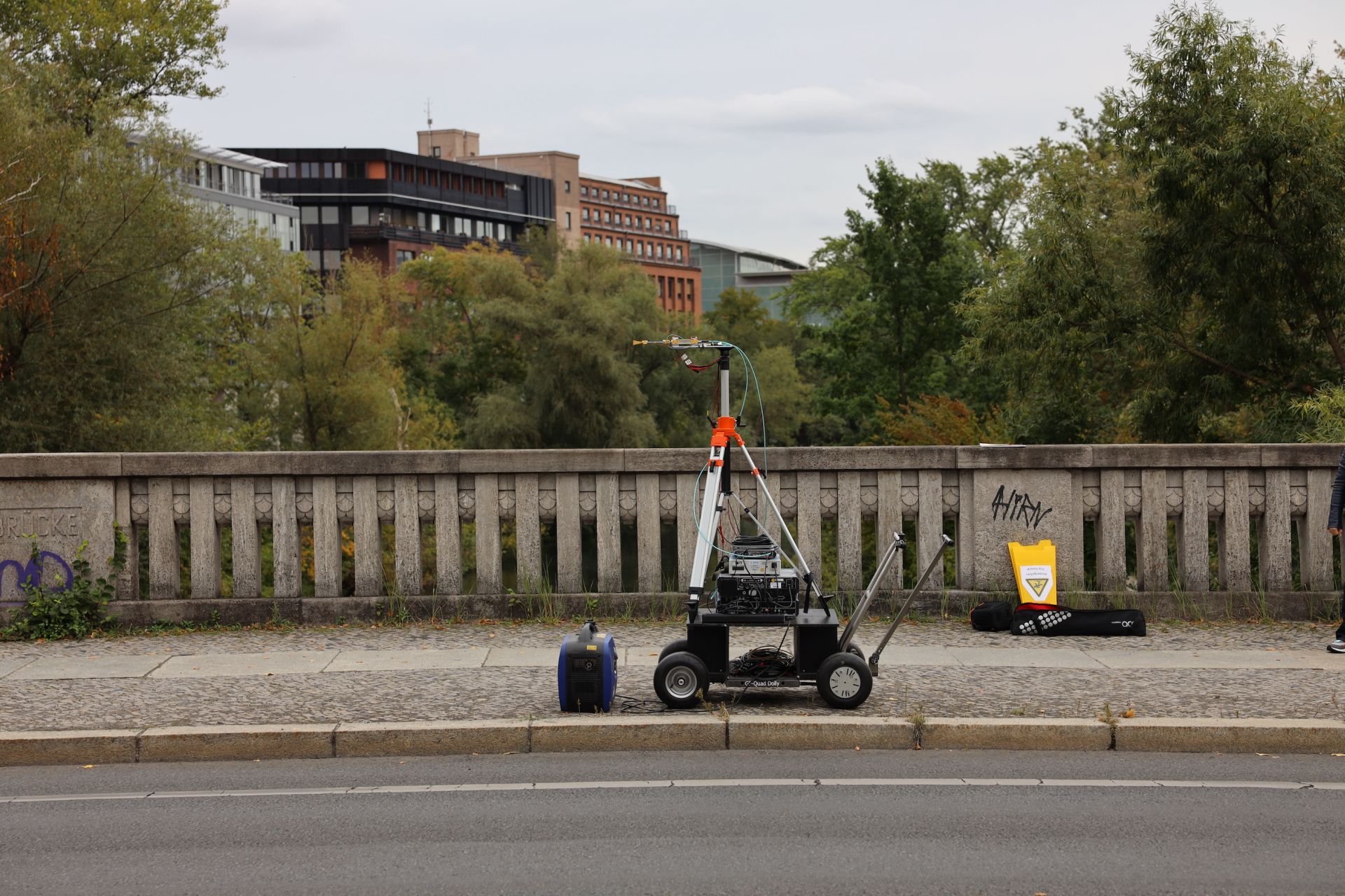 The receiver measurement setup on wheels can be seen on a traffic bridge with trees and buildings in the background.
